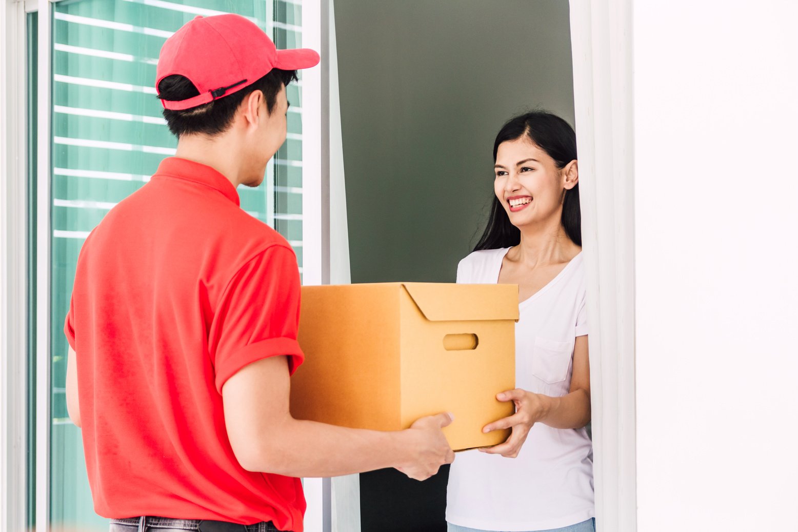 Woman accepting a delivery boxes from delivery man in red uniform.courier service concept